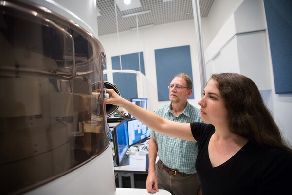 two researchers in front of large microscope in research lab 
