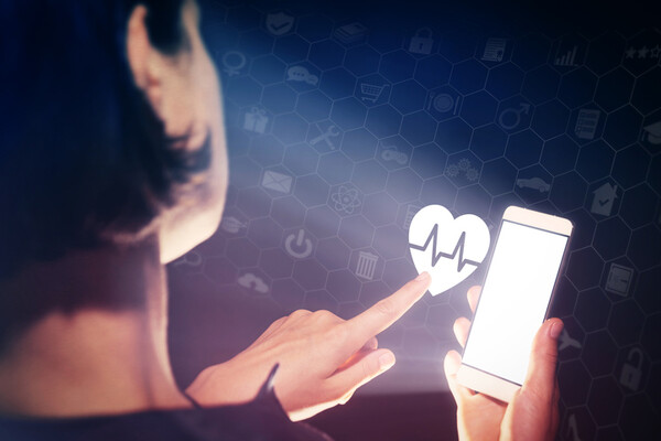 woman with cell phone clicking on an image of a heartbeat