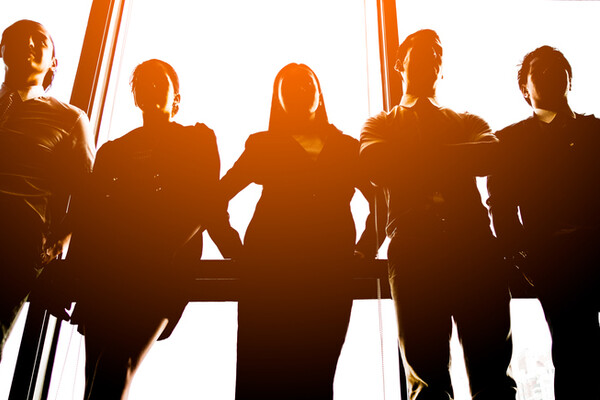 six people standing by a window backlit by the sun