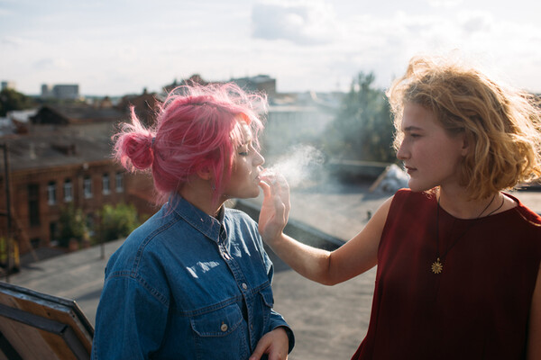 two teens smoking on a rooftop