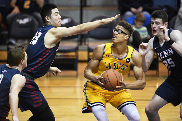 A trio of Penn basketball players guard a La Salle player with the ball