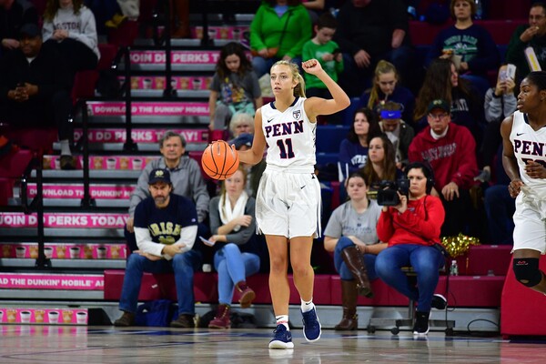 Kendall Grasela dribbles a basketball on court with one fist in the air