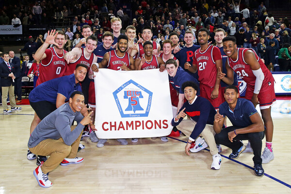 Penn basketball players holder the Big 5 championship banner on the Palestra court