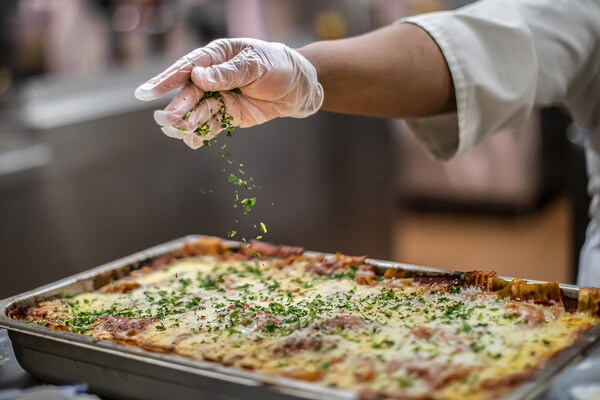 adding seasoning to lasagna at penn dining