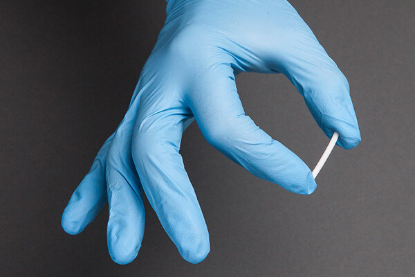 gloved hand holding naltrexone implant