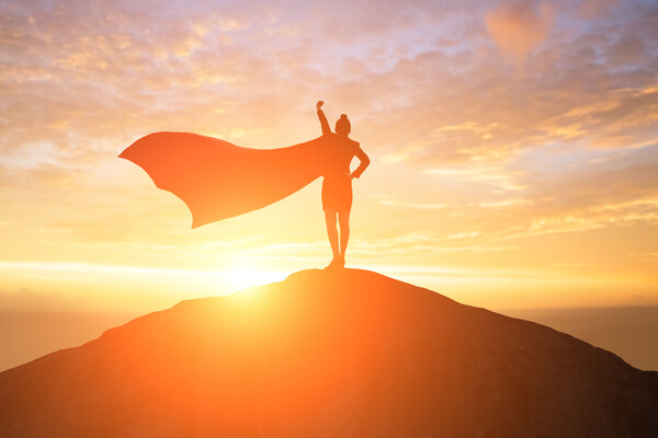 a silhouette of a woman with a cape standing on top of a hill