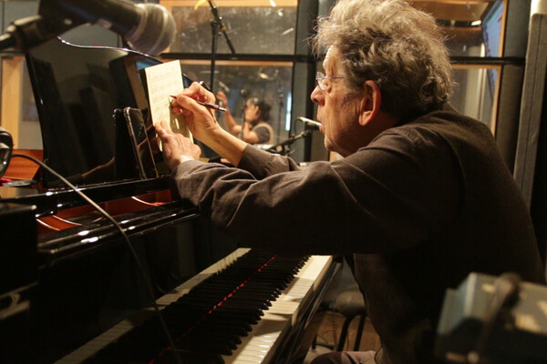 Philip Glass writing at piano