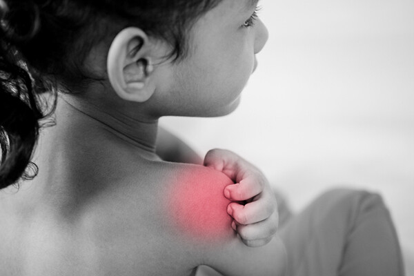 small child scratches bare shoulder that looks irritated.