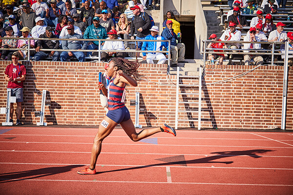 Uchechi Nwogwugwu crosses the finish line on a track.