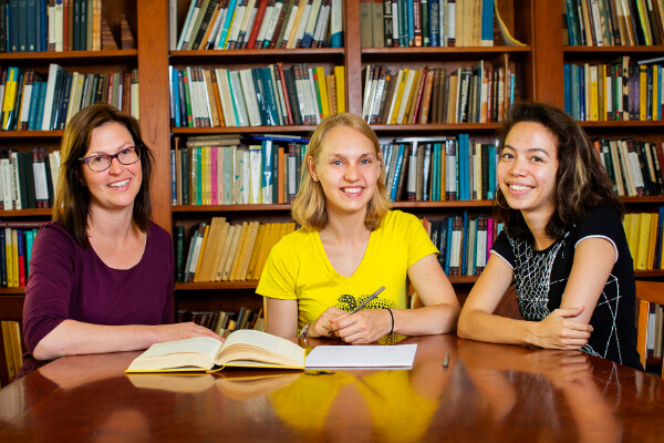 three people sitting at a table inside a library 