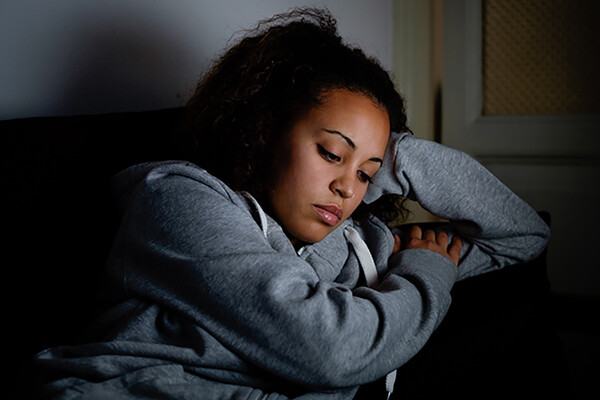 young person sits forlornly on couch.
