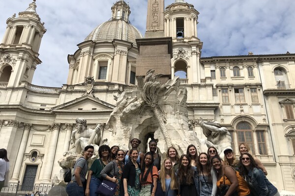 A group of people standing in front of a white statue in Rome, Italy. 