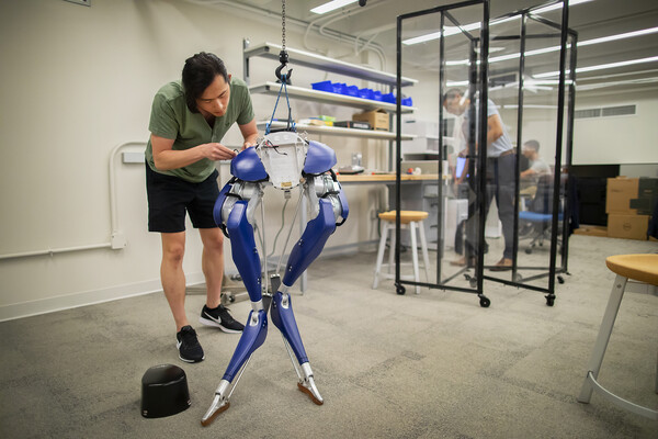 Michael Posa works on CASSIE, a legged robot in a lab.