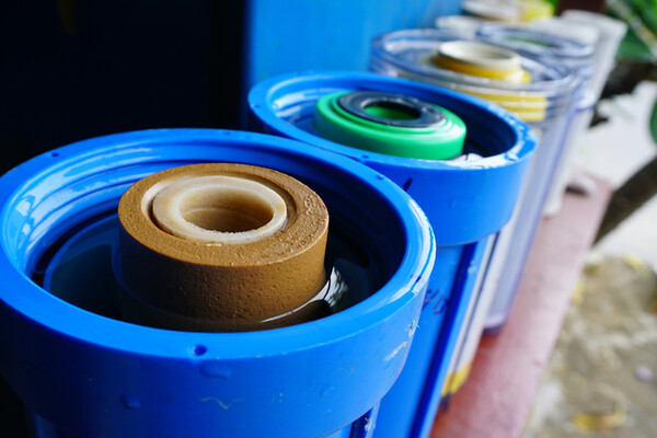 a line of cylinders with used water filters on a bench outside