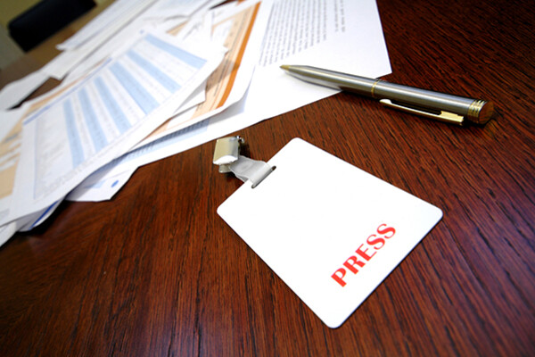 Press pass on a table surrounded by paperwork.
