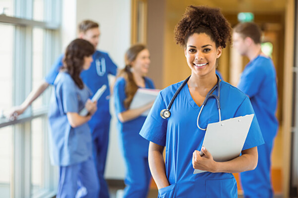 A med student of color in the foreground, four other med students in background of well-lit hallway.