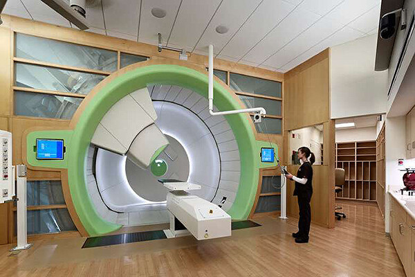 A clinic worker stands at the gantry of the Roberts Proton Therapy center machine.