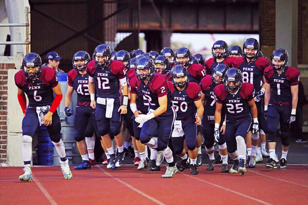 Members of the Sprint football team run onto the field before a game.