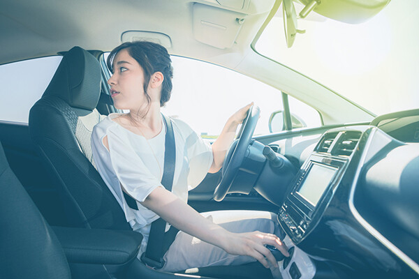 Teenager in a car's driver seat, looking over their shoulder.