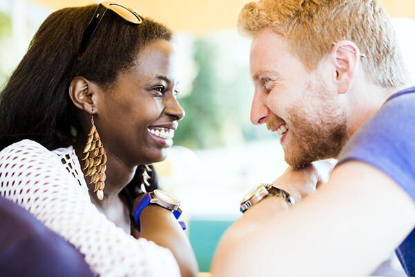 Two people face each other, smiling widely and looking into each other's eyes.