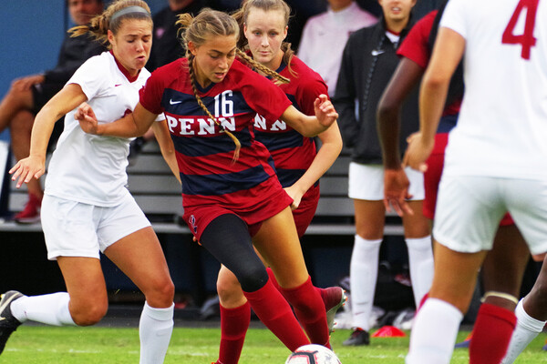 Junior midfielder Breukelen Woodard of the women's soccer team dribbles the ball between two defenders.