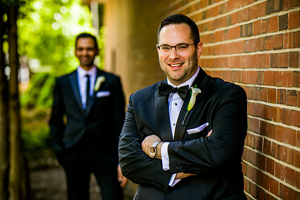 Jason Freedman in foreground on his wedding day to husband Neil, in background.