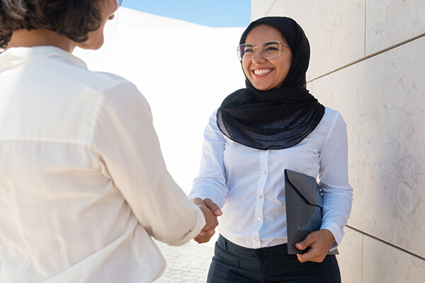 Two people shaking hands, one smiles confidently.