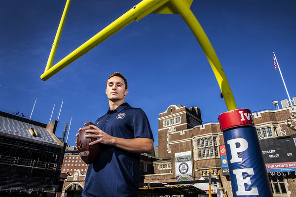 Senior quarterback Eddie Jenkins, captain of the sprint football team, holds a football on Franklin Field near the goal post.