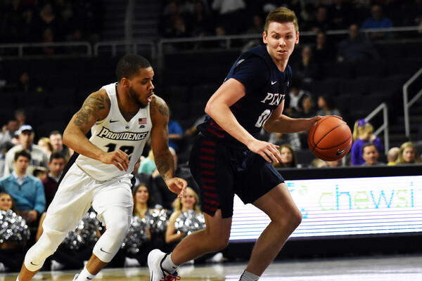 Against Providence in Rhode Island, senior guard Ryan Betley dribbles with the ball while being guarded by a defender.