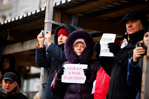Protesters holding posters saying: "Give us fair elections" and "For honest elections", outdoors in Moscow square.