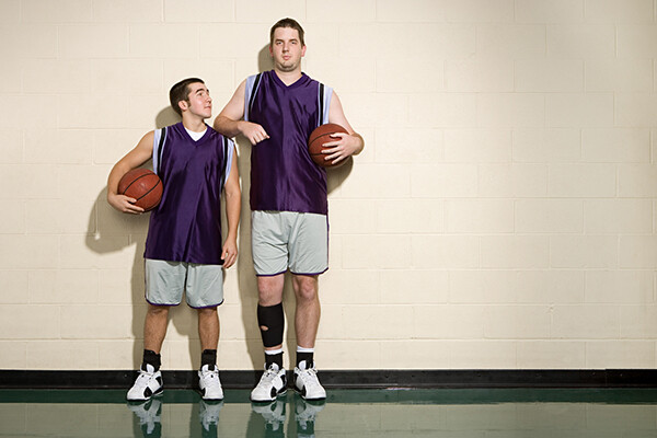 Two basketball players next to one another, one quite tall, the other quite short