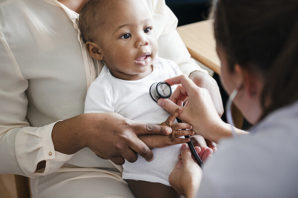 Baby looks at doctor who is checking their chest with a stethoscope