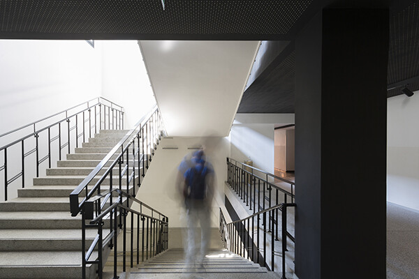 Teen wearing a backpack seen from behind walking down a flight of stairs