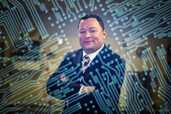 Nick Falcone standing with arms crossed with computer graphic renderings superimposed over the image.