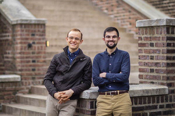 Two men stand in front of the brick and stone stairway leading to the Penn Museum