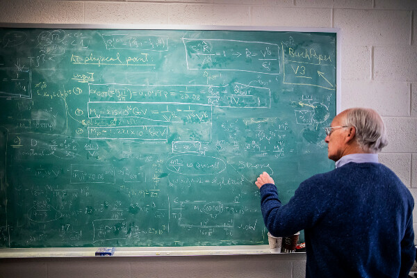 a person standing in front of a chalkboard covered in equations