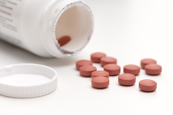 An opened bottle of ibuprofen will pills laying in front.
