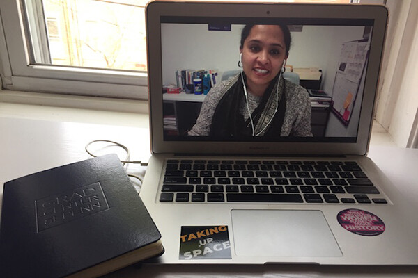 open laptop on a desk shows a video chat with a person wearing earbuds in an online learning environment