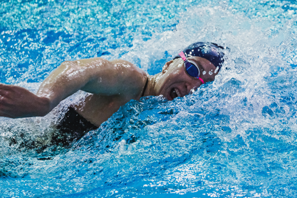 Catherine Buroker takes a breath while swimming in a pool during a meet.