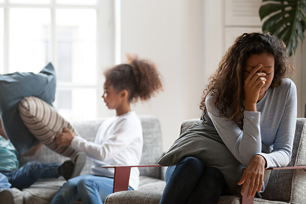 Parent turning away from kids while they play-fight on the couch