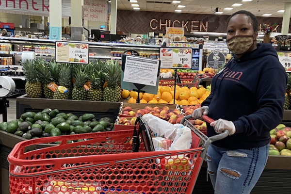 Person wearing a face mask in a grocery store standing next to a shopping cart. 