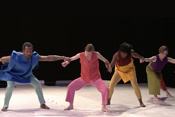 Members of a dance troupe linking arms in a line during a performance