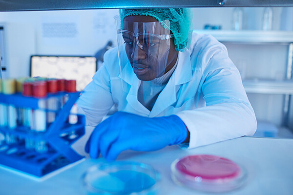 Medical professional wearing PPE using lab equipment in a lab.