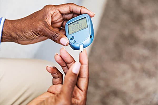 A pair of hands using a personal blood sugar measuring device.