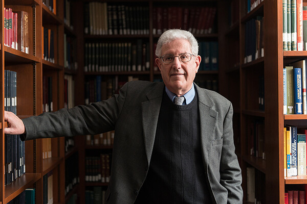 Person in glasses is surrounded by bookcases.
