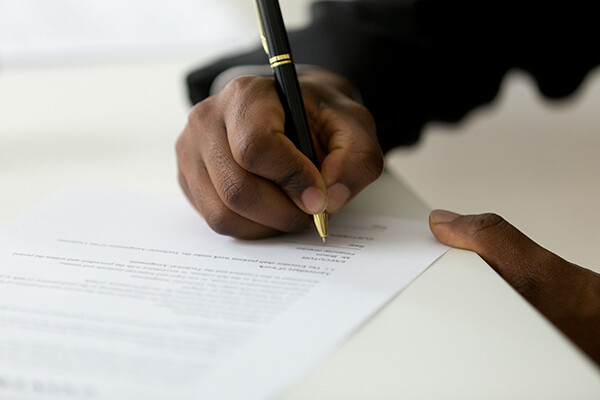 hand holding pen signing paperwork
