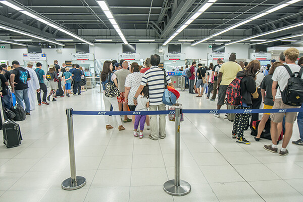 Three long lines of standing people at an airport.