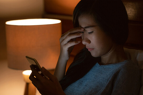 Person sitting with a cell phone who appears to be in pain reading a message