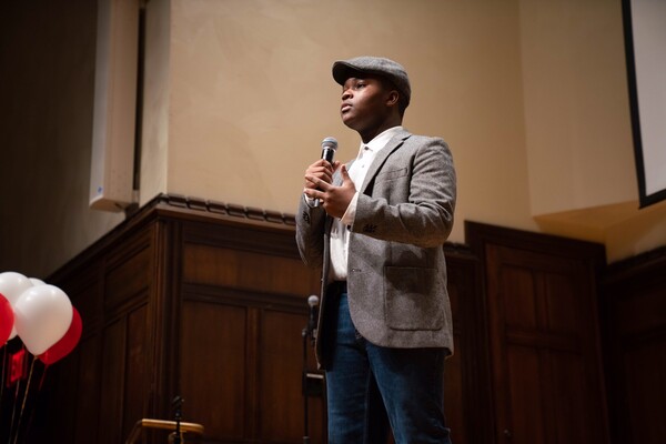 Student standing on stage speaking into a microphone