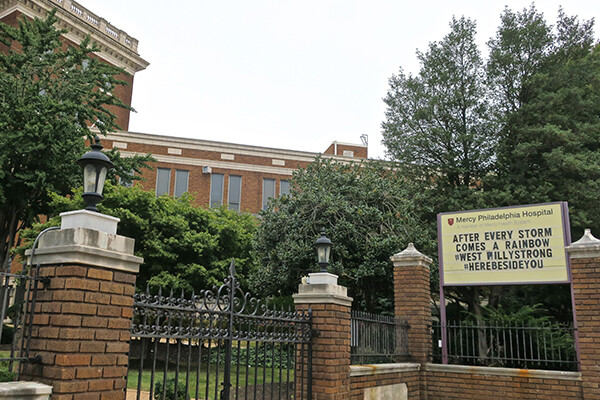 Front gate at Mercy Philadelphia Hospital with a sign reading “After every storm comes a rainbow. West Philly Strong. #HereBesideYou.”